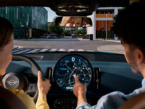 Vediamo una giovane coppia all'interno di una MINI intenta a consultare il navigatore.